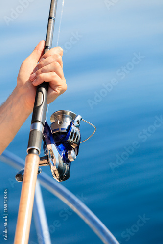 Man holding fishing rod, blue in background