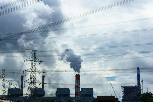 high voltage 500 KV transmission line and pylon with coal fire power plant release steam from stack in the morning background. electricity or climate change concept.