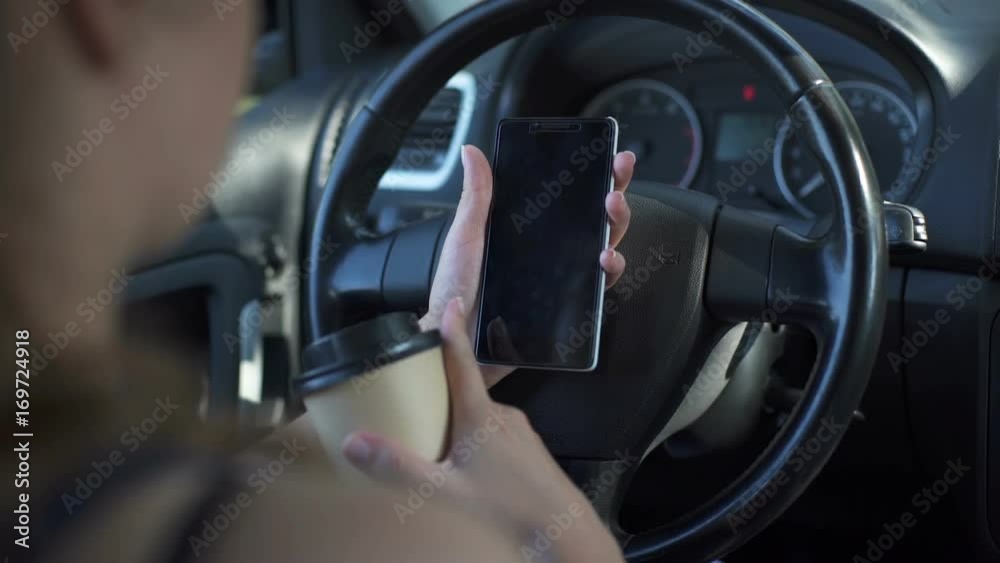 Woman sitting in the car using telephone and drinking coffee Woman sitting in the car using telephone and drinking coffee