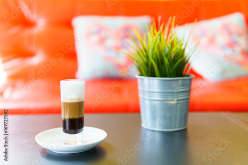 Latte macchiato or espresso macchiato with mock up plant on the table in cafe. coffee menu concept.