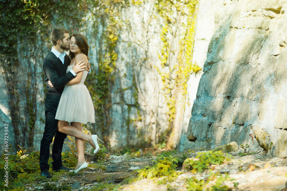 Pretty bride in short dress stands before a groom while he holds her tender Pretty bride in short dress stands before a groom while he holds her tender