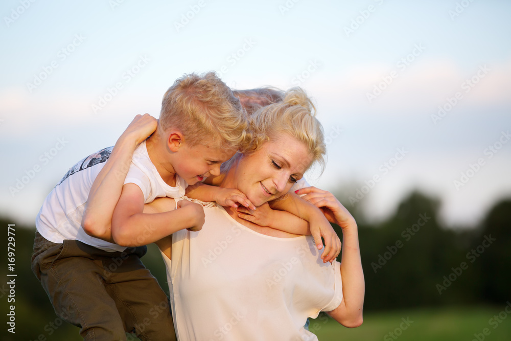 Fototapeta premium woman romps with her two sons on the grass