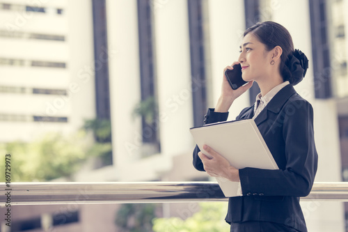 Young Beautiful business woman in city using smartphone for work. Young Business Woman Workwith Smartphone  Concept. Asian Woman Talking for Business Project with Partner. vintage tone. photo