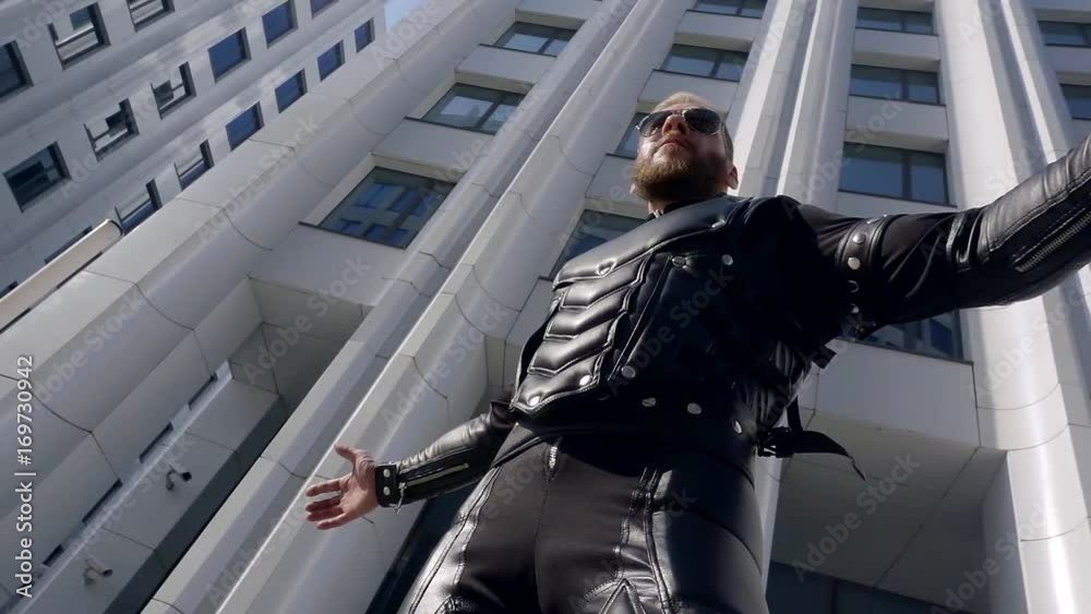 slow motion. 500 frames a second. young stylish middle-aged man with a beard in sunglasses day in the city is in the cyber suit from modern materials in black slow motion. 500 frames a second. young stylish middle-aged man with a beard in sunglasses day in the city is in the cyber suit from modern materials in black