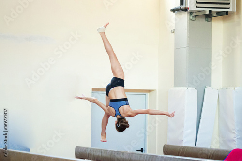 beautiful girl is engaged in sports gymnastics on a log.