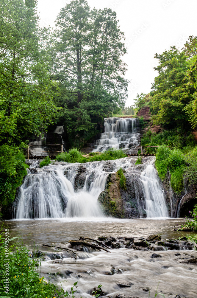 Cascaded waterfall in a green forest. Dzhurinsky waterfall Ukraine.