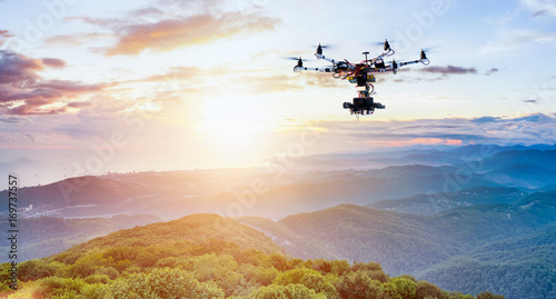 The drone with the professional camera takes pictures of the misty mountains at sunset photo
