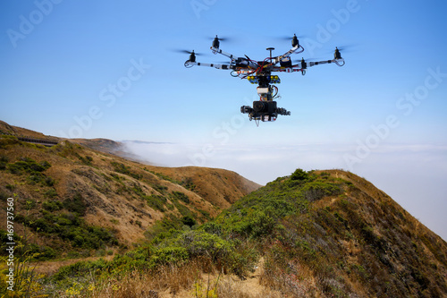 Drone with professional cinema camera flying over Pacific Ocean covered fog and the mountains in California