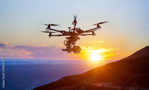 The drone with the professional camera takes pictures of the misty mountains at sunset. Uav drone copter flying with digital camera. Hexacopter drone with high resolution digital camera on the sky.