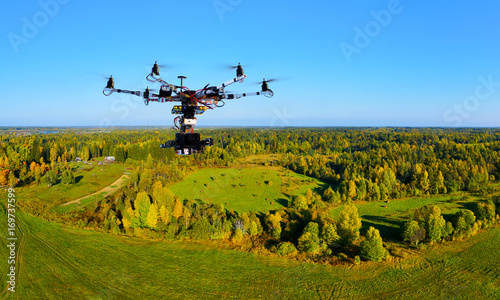 hexacopter with professional cinema camera flying over a autumn park in fall colors under morning light with deep long shadows