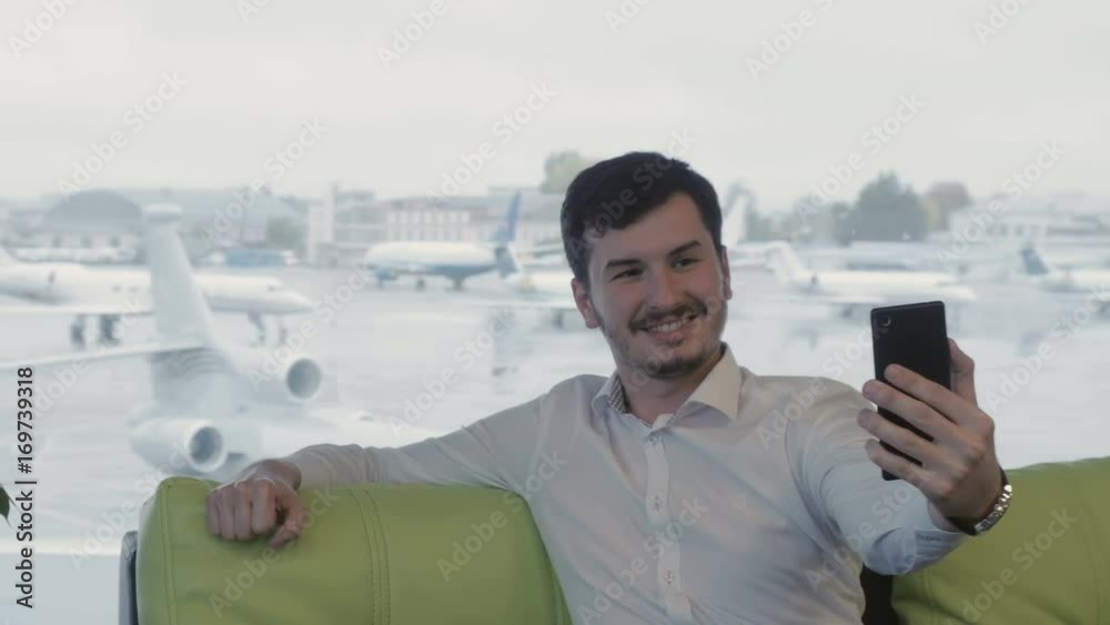 Businessman takes a selfie in the airport lounge hall Businessman takes a selfie in the airport lounge hall