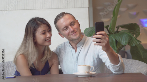 Multicultural couple taking self portrait using smartphone.