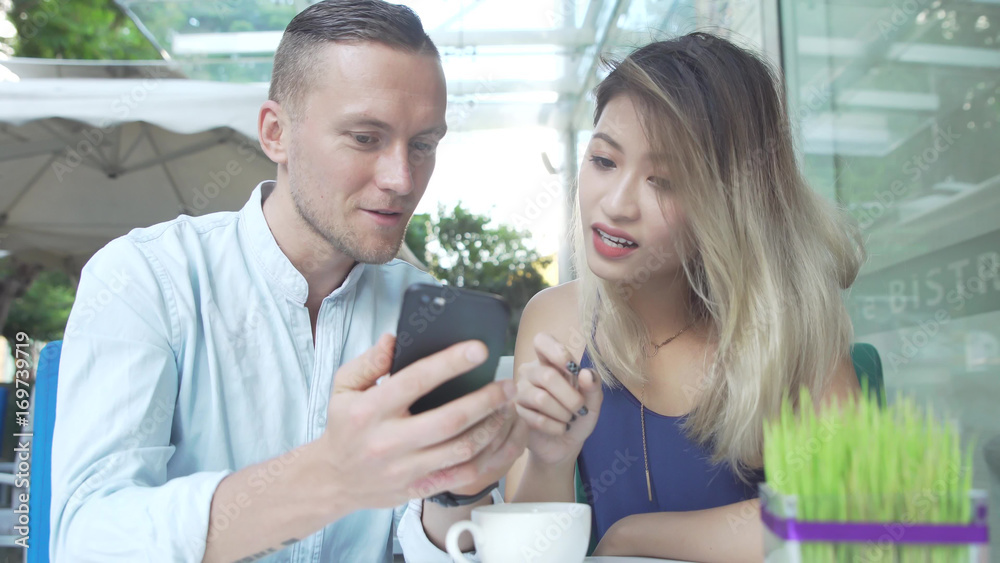 Fototapeta premium Multicultural couple watch movie together on smartphone