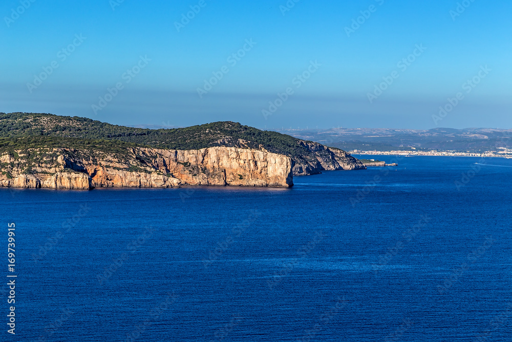 Sardinia, Italy. Picturesque coastal rocks. On the horizon, the city of Alghero