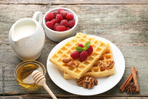 Sweet waffle with raspberries, milk and honey on wooden table