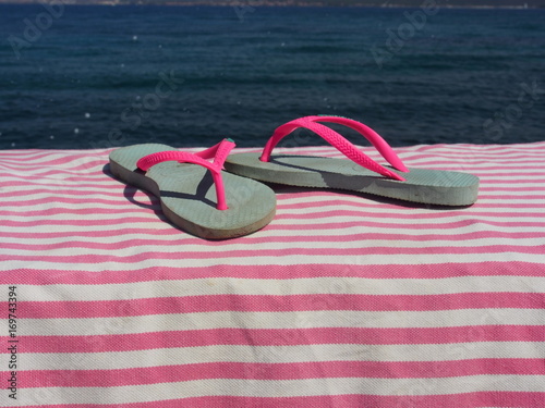 Badeurlaub: Rosa Kinder-Flip-Flops auf Strandtuch