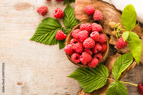 Raspberry in a bowl, berries and leaves on a shabby  wood. Top view