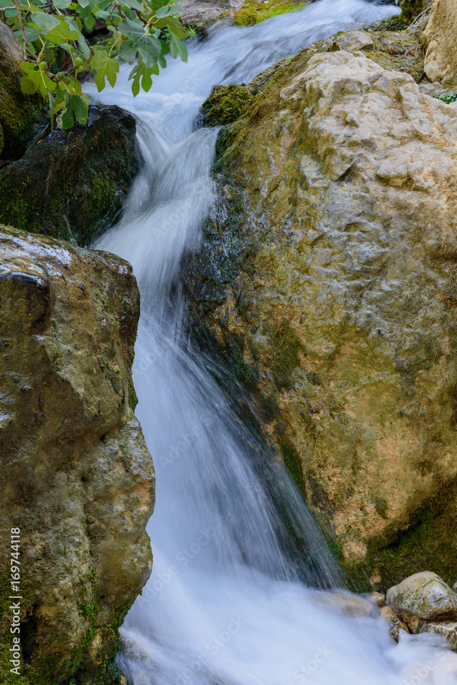 Obraz premium Close up of mossy rock with blurred flowing water rushing downstream