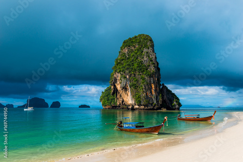 high rock in the sea, rain cloud and Thai boats near the shore © kosmos111