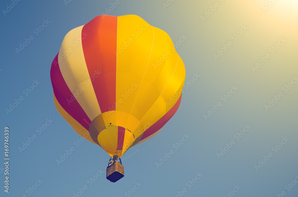 Fototapeta premium Colorful air balloon in a blue sky in sunlight. Toned