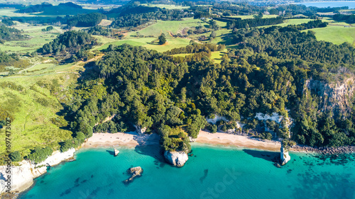 Aerial view on a small beach surrounded by rocks and forest. Coromandel, New Zealand