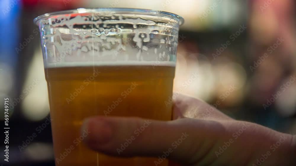 Close Up Tilt to Beer Picked Up in Bar. a hand held tilting shot up a beer in a plastic cup at a bar. Beer is picked up and placed back down
Close Up Tilt to Beer Picked Up in Bar. a hand held tilting shot up a beer in a plastic cup at a bar. Beer is picked up and placed back down