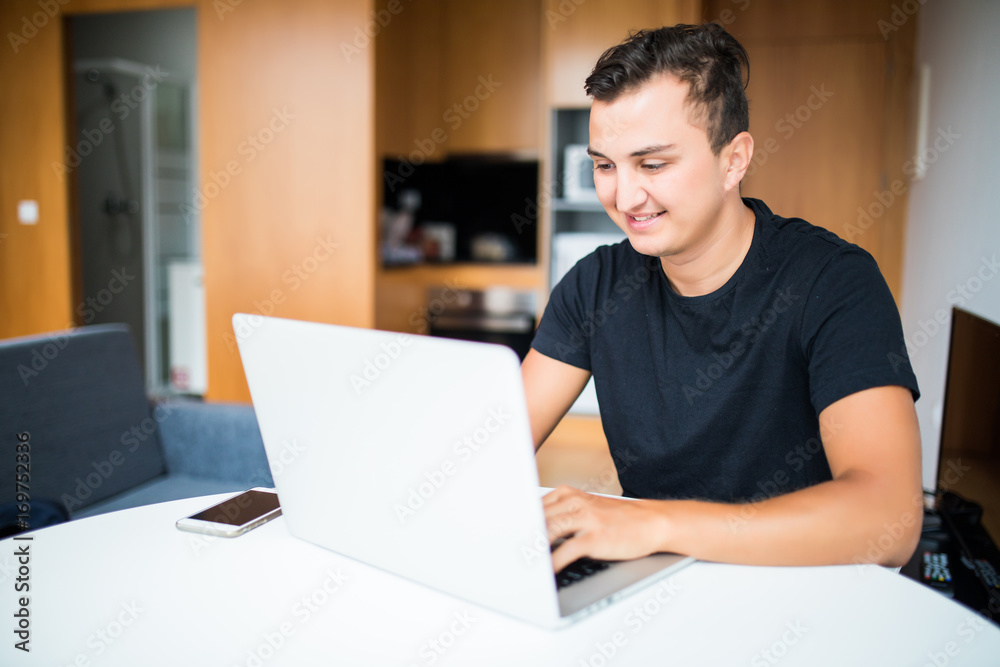 Self employed man with smile working from home on laptop