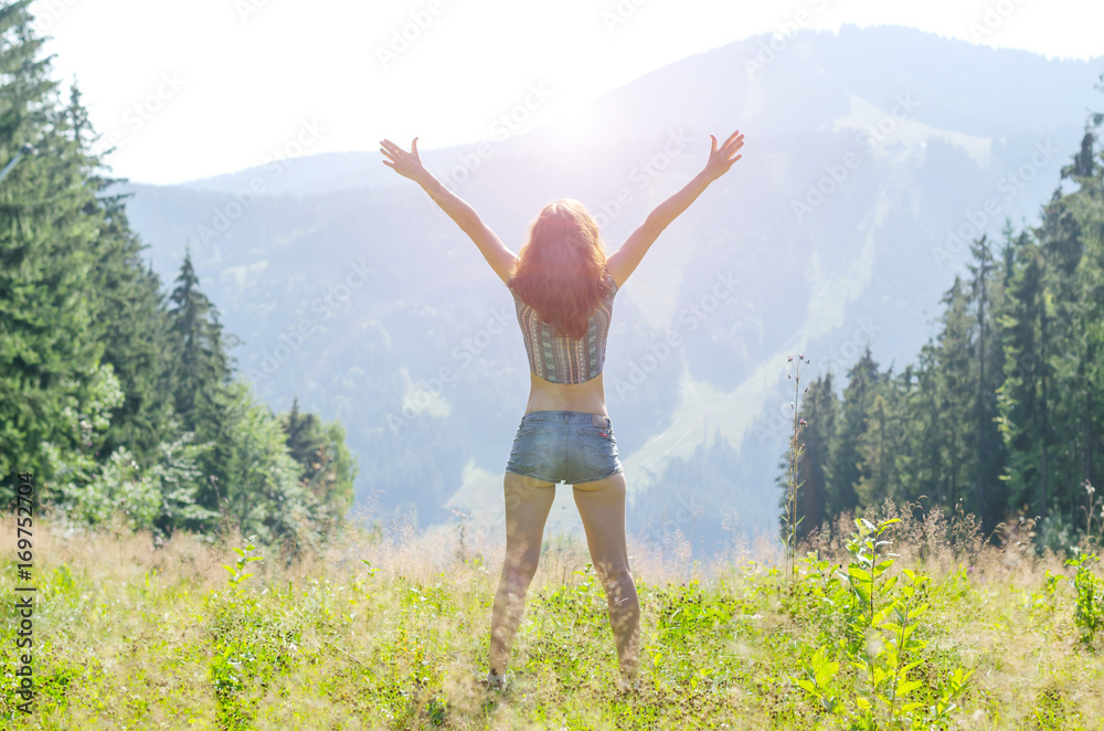 A young woman opens her hands on the top of the mountain, free space. A young woman opens her hands on the top of the mountain, free space.
