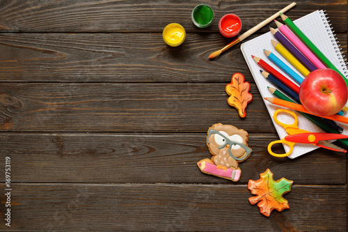 Back to school concept background with colored pencils, red appple and gingerbread on wooden table