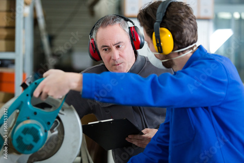 workers wearing earmuffs using circular saw