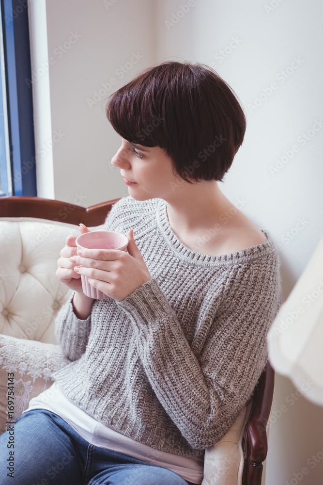 Woman having coffee while sitting on sofa at home Woman having coffee while sitting on sofa at home