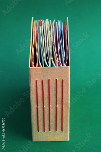 A colorful, handmade junk journal. Made from a recycled box and random paper such as book pages, envelopes and wall paper. Five signatures are stitched in with red thread.