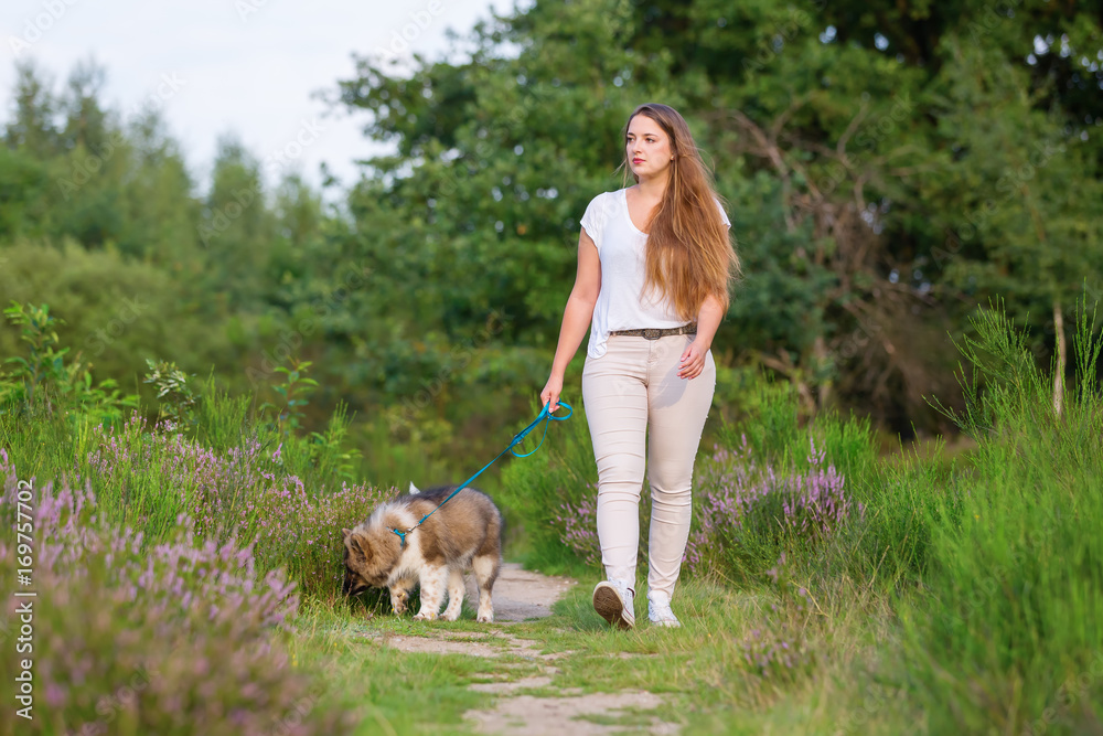 woman walking with an elo puppy at the leash woman walking with an elo puppy at the leash