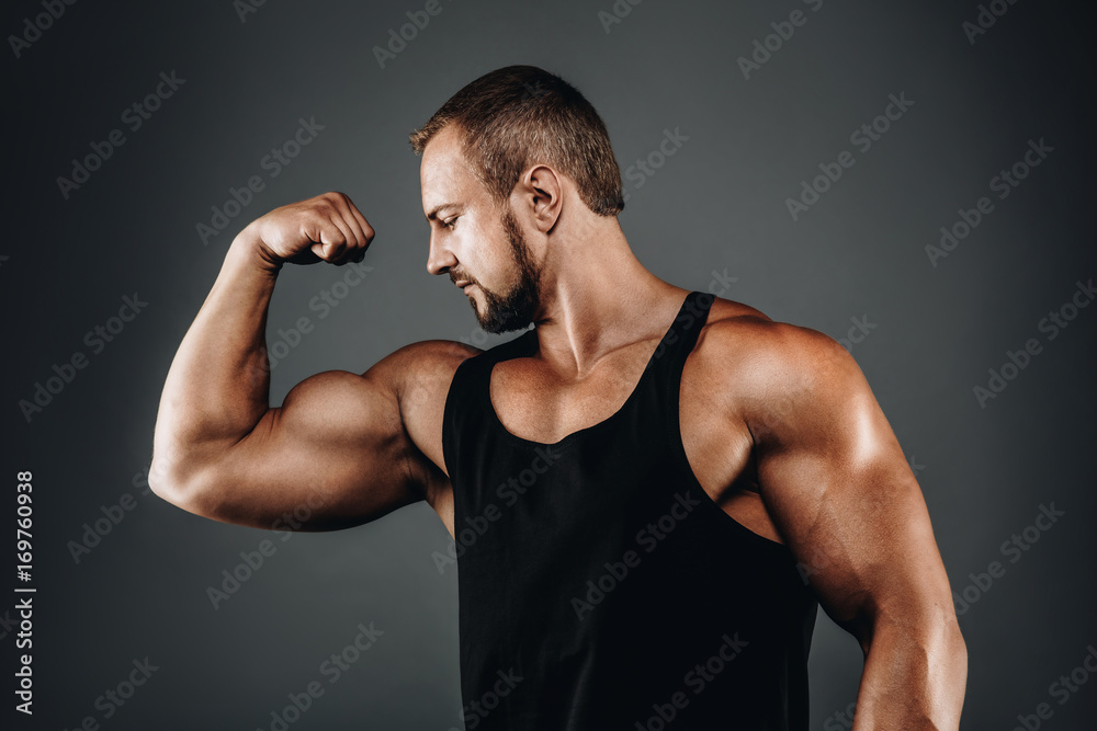 Strong athletic bodybuilder posing with perfect abs, shoulders, biceps, and triceps  chest, personal fitness trainer flexing his muscles