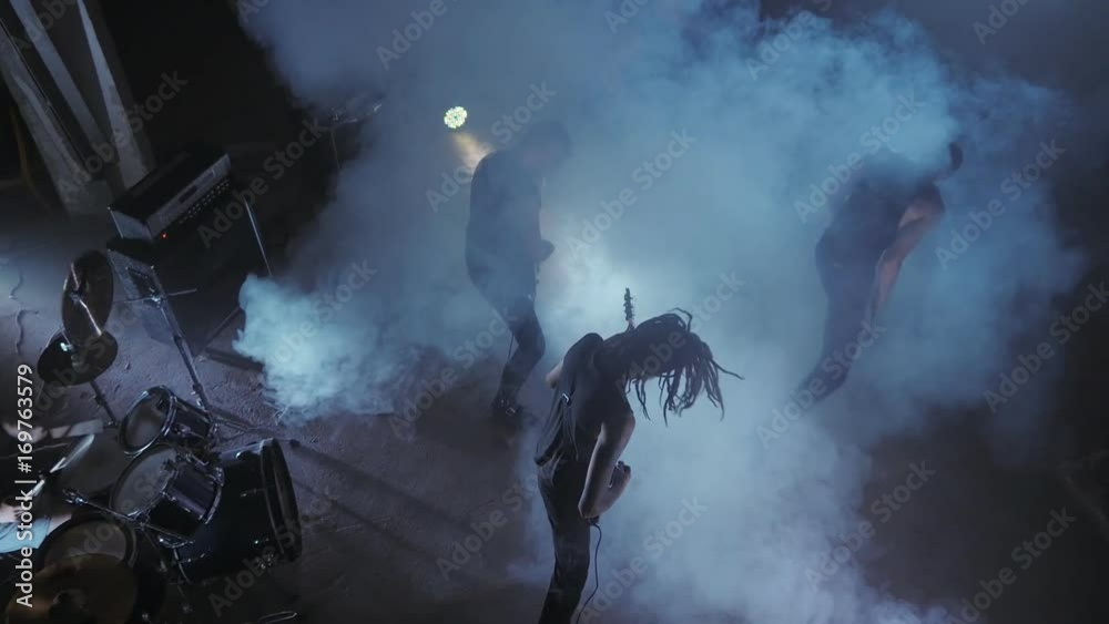 Concert rock band performing on stage with Frontman, guitarists and drummer. Music video punk, heavy metal or rock group.
