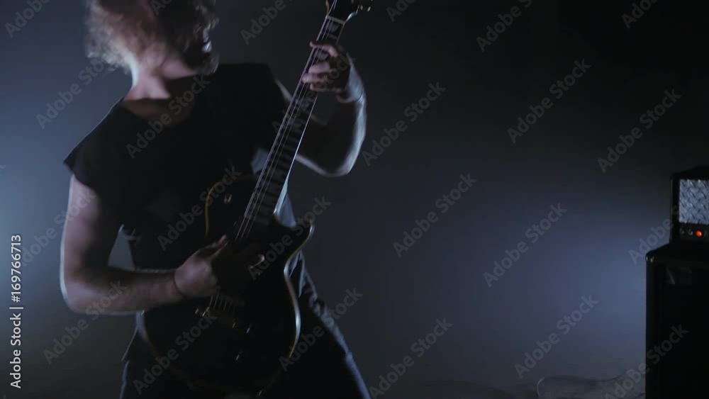 Concert rock band performing on stage with guitarist. man plays the electric guitar. Music video punk, heavy metal or rock group.