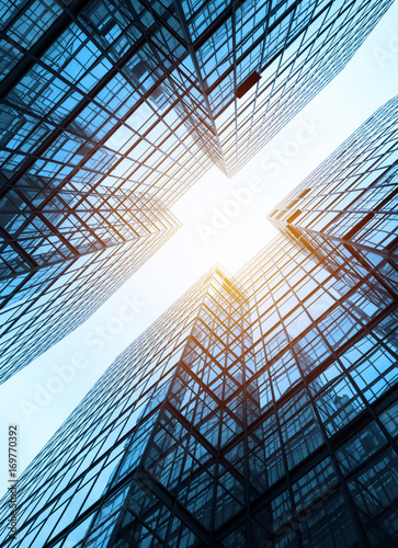 Low angle view of city skyline buildings, blue sky and glass mirrored facades.
