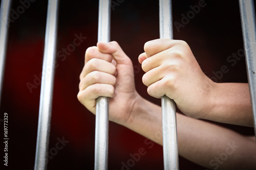 Hands of a child grabbing prision bars photo