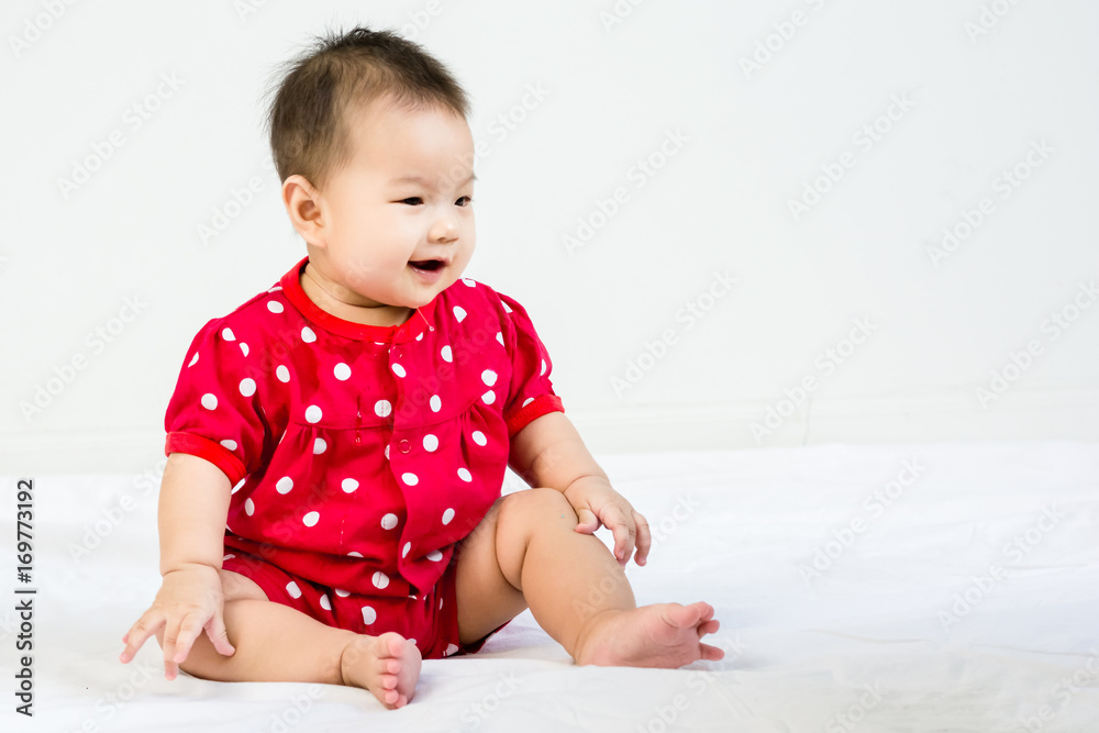 Portrait of adorable baby sitting on a white floor and smiling with copyspace
