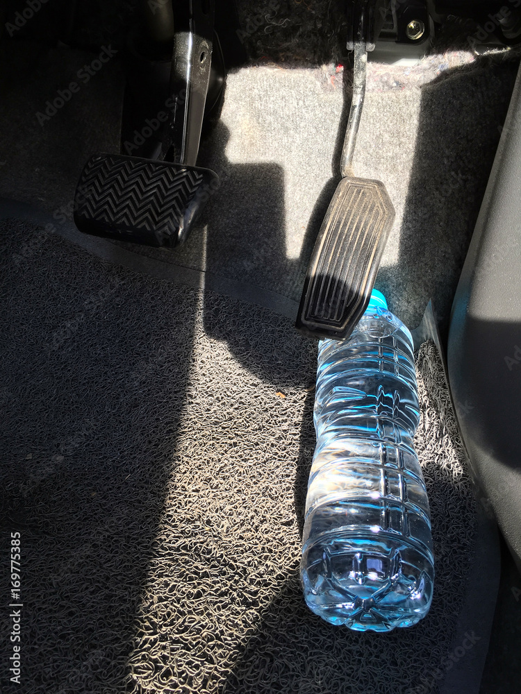 Water bottle getting stuck in the car accelerator and brake peddle  demonstrating the danger of the inability to apply the brake or  acceleration Stock Photo