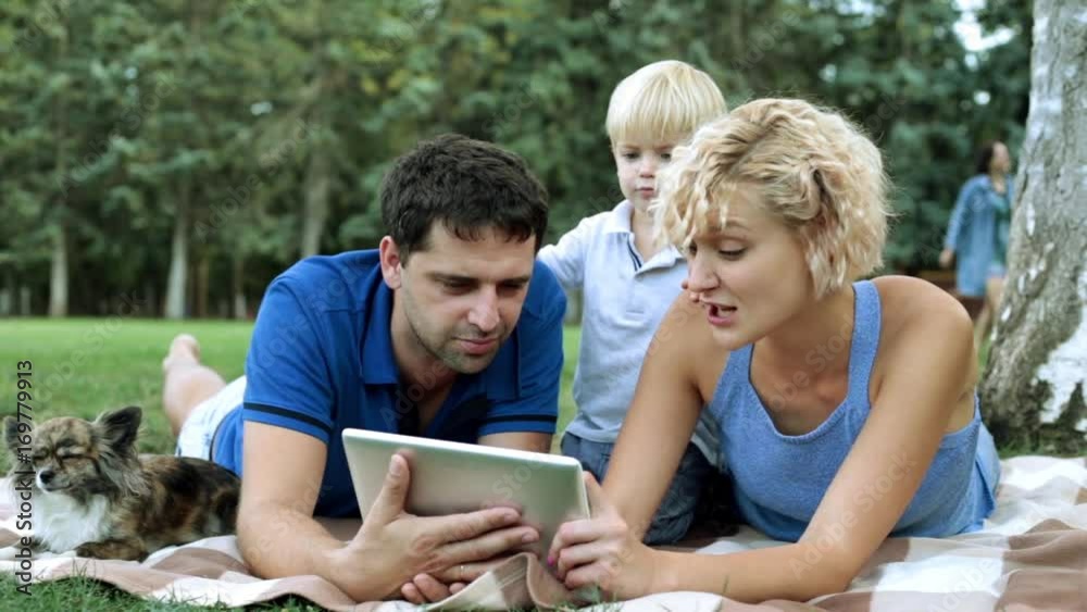 Happy family and digital technology. Family with a child and a tablet computer in the park. Happy family and digital technology. Family with a child and a tablet computer in the park.