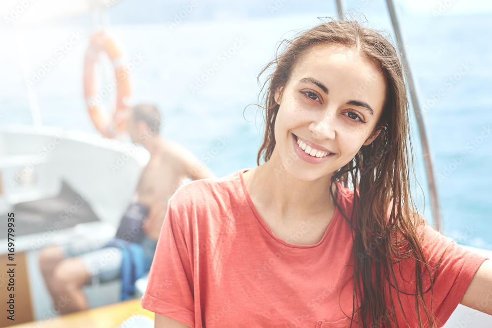 happy young smiling woman in the white boat on the cloudy sky background. woman wearing in a red t-shirt looks very happy. Caucasian female model happy young smiling woman in the white boat on the cloudy sky background. woman wearing in a red t-shirt looks very happy. Caucasian female model