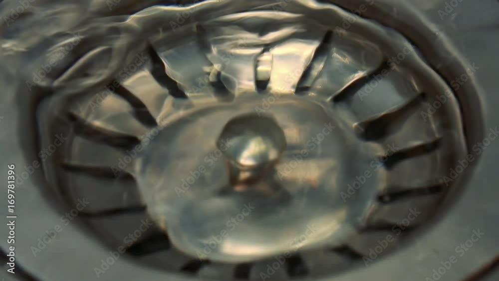 A kitchen sink is filled with water - closeup on the strainer A kitchen sink is filled with water - closeup on the strainer
