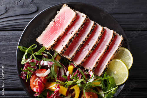 beautiful food: steak tuna in sesame, lime and fresh salad close-up on a plate. Top view horizontal