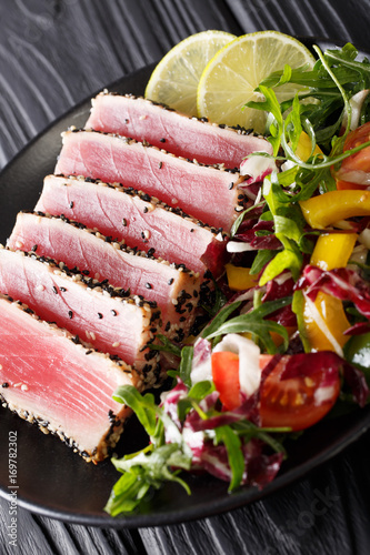 Close up of rare seared Ahi tuna slices with fresh vegetable salad. vertical