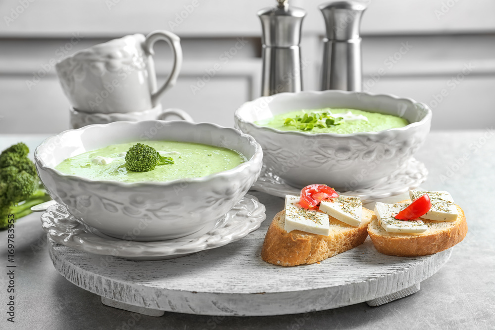Bowls with delicious broccoli soup on wooden tray Bowls with delicious broccoli soup on wooden tray
