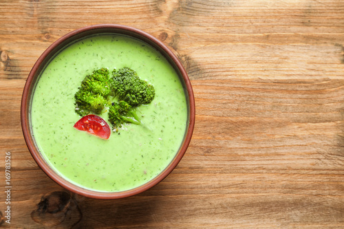 Bowl with delicious broccoli soup on wooden background