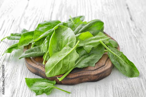 Wooden board with fresh spinach leaves on table