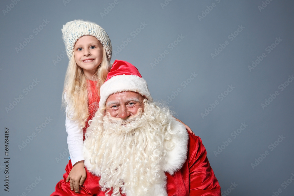 Cute little girl with Santa Claus against color background Cute little girl with Santa Claus against color background