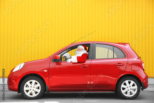 Photographie Authentic Santa Claus driving his red car, against yellow background